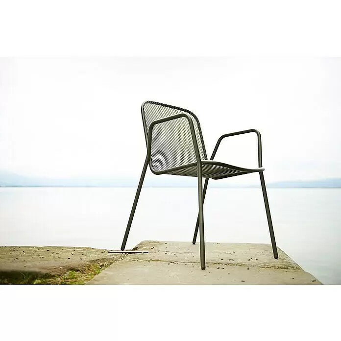 Acamp Gartensessel Alfredo - Stahl, Stapelbar, Schwarz, B x T x H: 55 x 60 x 83 cm, 6 Stk. - Dunkelgrauer Metallgitterstuhl mit Armlehnen, auf einer Betonplatte an einem ruhigen See platziert.
