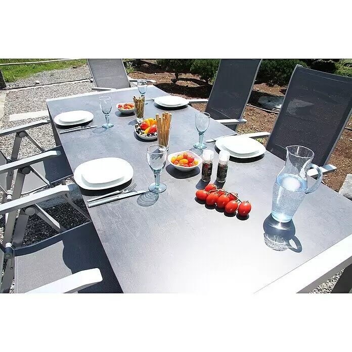 Acamp Gartenmöbel-Set Urban/Extensio - 5 -tlg., Aluminium, HPL, Textil, Klappbar, Anthrazit - Gedeckter Outdoor-Esstisch aus grauem Material mit passenden Stühlen in einer Gartenszene.
