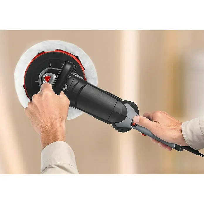 Skil Pulidora 1144AA - 1.200 W, 180 mm, 1.000 r.p.m. - 3.600 r.p.m. - Primer plano de una pulidora en acción, sujeta por dos manos, creando un acabado brillante.\n