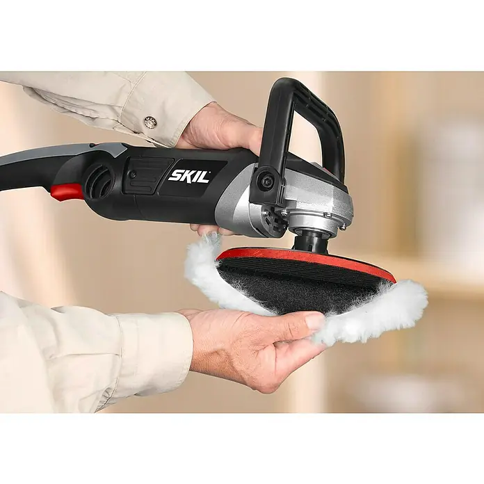Skil Pulidora 1144AA - 1.200 W, 180 mm, 1.000 r.p.m. - 3.600 r.p.m. - Primer plano de una pulidora SKIL con un accesorio de pulido suave, sostenida en las manos de una persona.