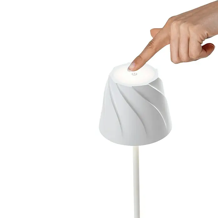 Starlux Akku-Tischleuchte Loreo - 4 W, L x B x H: 11 x 11 x 36 cm, Weiß, Warmweiß - Ein Finger berührt den Ein-/Ausschalter einer modernen, weißen Tischleuchte mit spiralförmigem Design auf einem schwarzen Hintergrund.