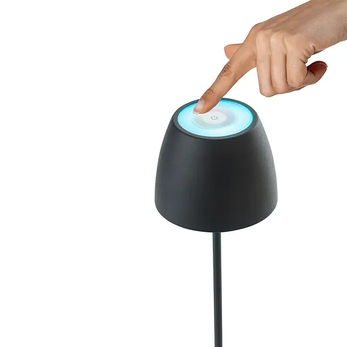 Lavida Lámpara de sobremesa a batería Silea - 3,3 W, Antracita, Color de luz: RGBW - Una mano toca la parte superior iluminada de una moderna lámpara de mesa negra que emite una suave luz azul.