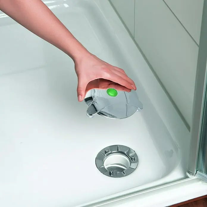 Abfluss-Fee Verschlussstopfen - Mit Duftstein, Einsatzbereich: Dusche - Eine Hand platziert einen verchromten Duschabflussdeckel mit einem grünen Knopf in einer weißen Duschwanne, um den Abfluss zu verschließen.