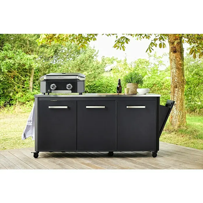 Cozze Outdoorküchen-Modul - Schwarz, B x T x H: 180 x 60 x 90 cm - Eine stilvolle, schwarze Outdoor-Küche mit Grillplatte auf einer Holzterrasse, umgeben von üppigem Grün. Perfekt für kulinarische Erlebnisse im Freien.