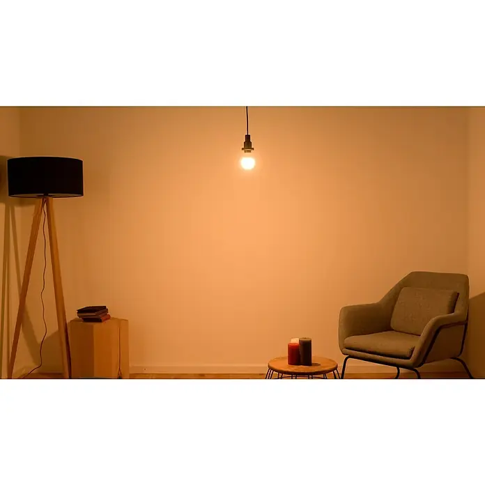 Osram LED-Lampen Set Glühlampenform E27 matt - E27, Nicht Dimmbar, Warmweiß, 806 lm, 9 W, 3 Stk. - Eine stimmungsvolle Raumszene mit einem eleganten Stehlampe mit schwarzem Schirm und einer einzelner Glühbirne, die warmes Licht spendet.