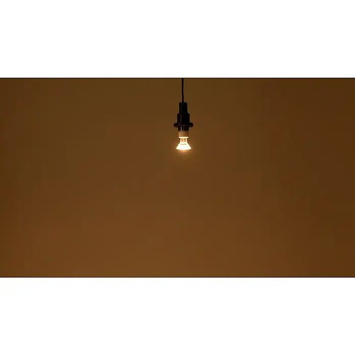 Osram LED-Lampen Set Reflektor GU10 - GU10, Nicht Dimmbar, Warmweiß, 350 lm, 4,3 W, 3 Stk. - Nahaufnahme einer einzelnen, warm leuchtenden Glühbirne, die von der Decke hängt, vor einem neutralen Hintergrund.