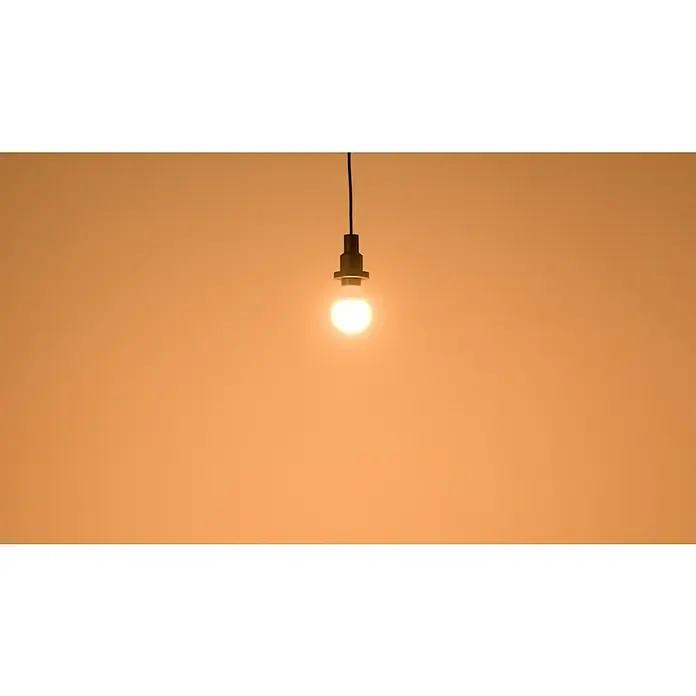 Osram LED-Lampen Set Glühlampenform E27 matt - E27, Nicht Dimmbar, Warmweiß, 806 lm, 9 W, 3 Stk. - Glühbirne an einem Kabel vor orangefarbenem Hintergrund, die Licht spendet. Minimalistisch und dekorativ.