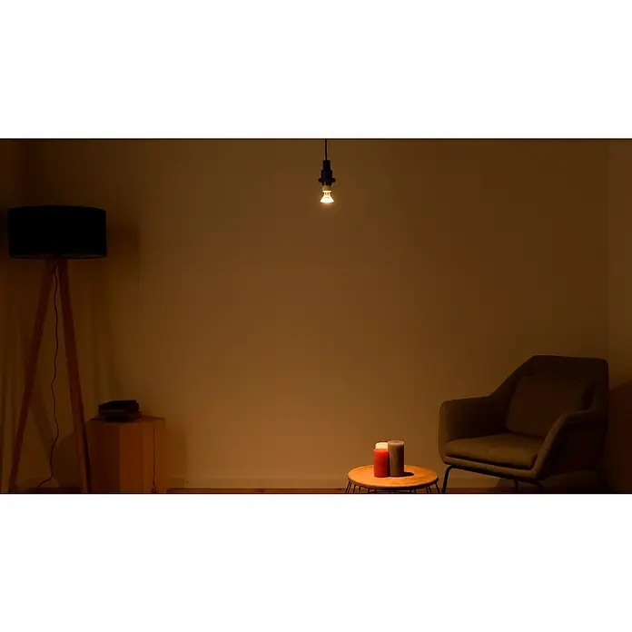 Osram LED-Lampen Set Reflektor GU10 - GU10, Nicht Dimmbar, Warmweiß, 350 lm, 4,3 W, 3 Stk. - Gedämpfte Innenraumszene mit Stehlampe, Glühbirne und Sessel, die eine gemütliche Atmosphäre schaffen.