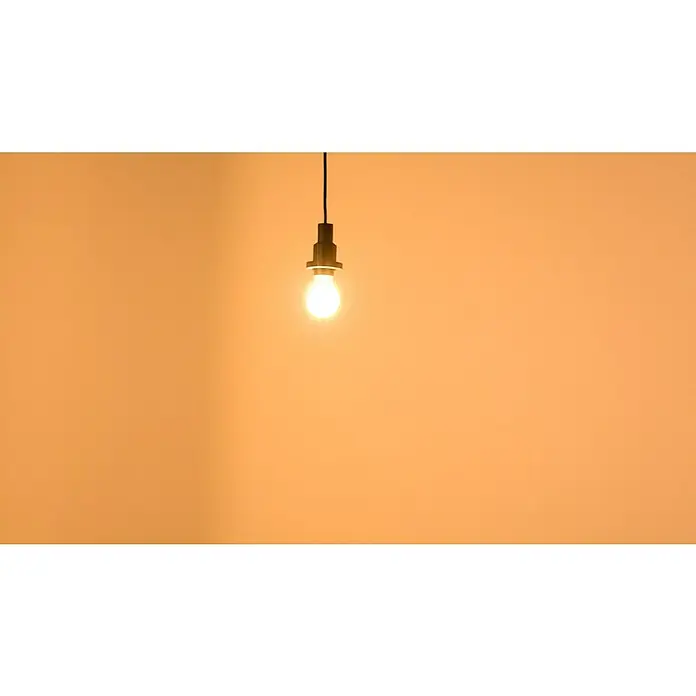 Osram LED-Lampe Glühlampenform E27 klar - E27, Nicht Dimmbar, Warmweiß, 806 lm, 7 W - Helle Glühbirne mit schwarzer Fassung an einem Kabel vor einem orangefarbenen Hintergrund. Die Glühbirne strahlt warmes Licht aus.