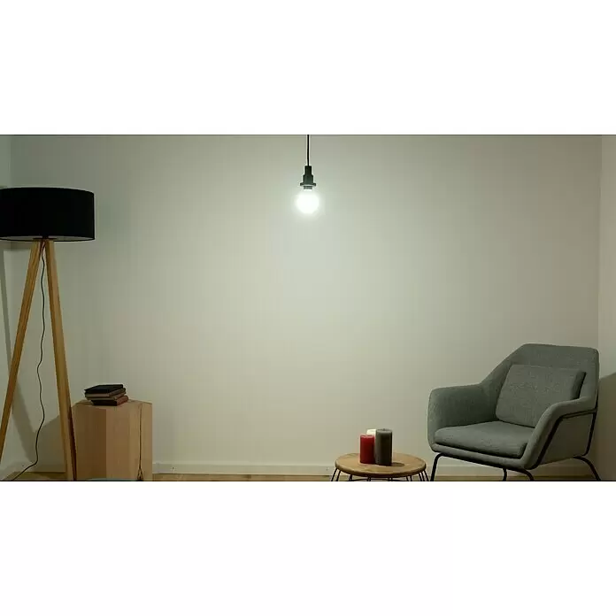 Osram Star LED-Lampe Glühlampenform E27 matt - E27, Nicht Dimmbar, Tageslichtweiß, 806 lm, 8,5 W - Eine einzelne leuchtende LED-Glühbirne hängt an einem schwarzen Kabel und beleuchtet einen modernen Wohnraum.
