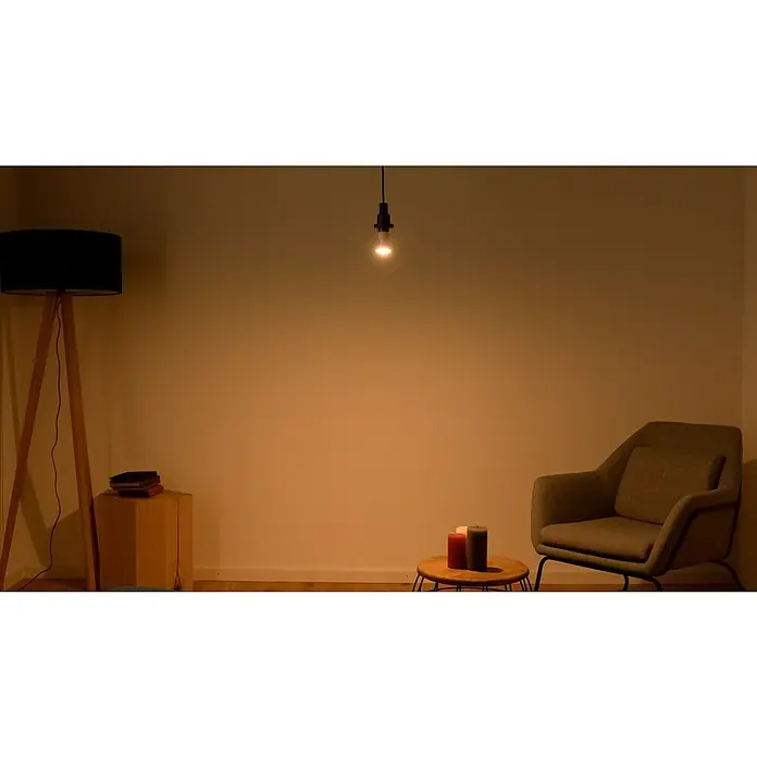Osram LED-Lampe Star+ PAR16 - GU10, Dimmbar, RGBW, 250 lm, 4,5 W - Einladendes Wohnzimmer mit Stehlampe, Hängelampe, Sessel und Kerzen, die eine warme, gemütliche Atmosphäre schaffen.