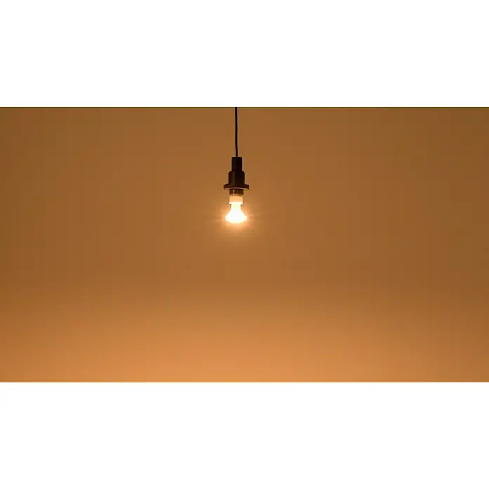 Osram Star LED-Lampe Reflektor GU10 - GU10, Nicht Dimmbar, Warmweiß, 575 lm, 6,5 W - Nahaufnahme einer hängenden Glühbirne, die helles Licht in einem sanften, goldenen Ton ausstrahlt und eine warme Atmosphäre schafft.