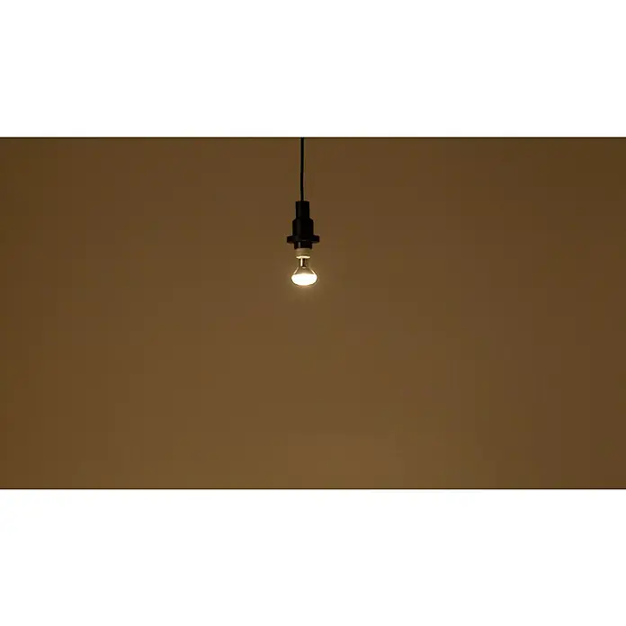 Osram Star LED-Lampe - E14, Nicht Dimmbar, Kaltweiß, 210 lm, 2,6 W - Nahaufnahme einer einzelnen, eingeschalteten Glühbirne, die von der Decke hängt und warmes Licht in einem dunklen Raum spendet.