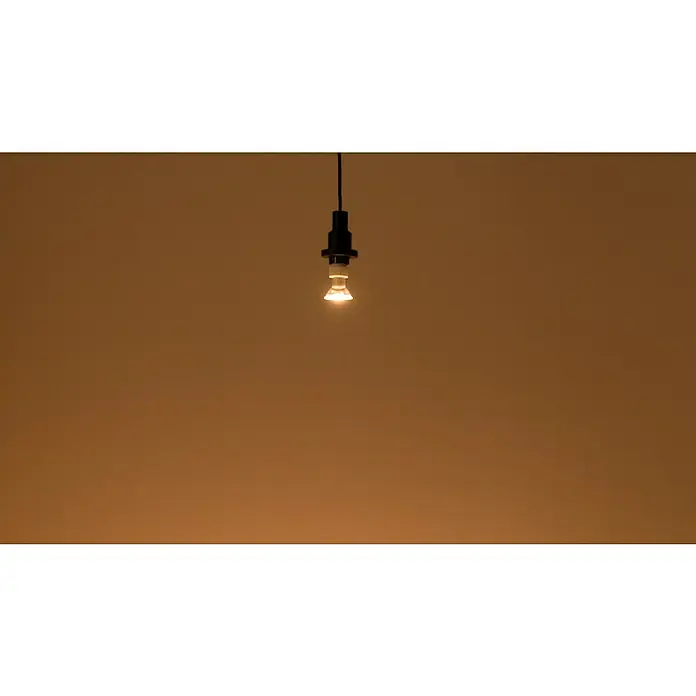 Osram LED-Lampe Reflektor GU10 - GU10, Dimmbar, Warmweiß, 575 lm, 8 W - Glühbirne mit Fassung und schwarzem Kabel vor einem warmen, hellbraunen Hintergrund für stimmungsvolles Licht.