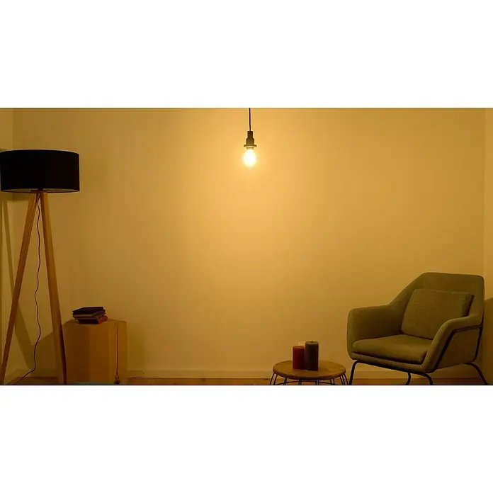 Osram LED-Lampe - E14, Nicht Dimmbar, Warmweiß, 110 lm, 10 W - Gemütliches Wohnzimmer mit Stehlampe, Sessel und Ambiente-Beleuchtung. Die Einrichtung schafft eine warme und einladende Atmosphäre.