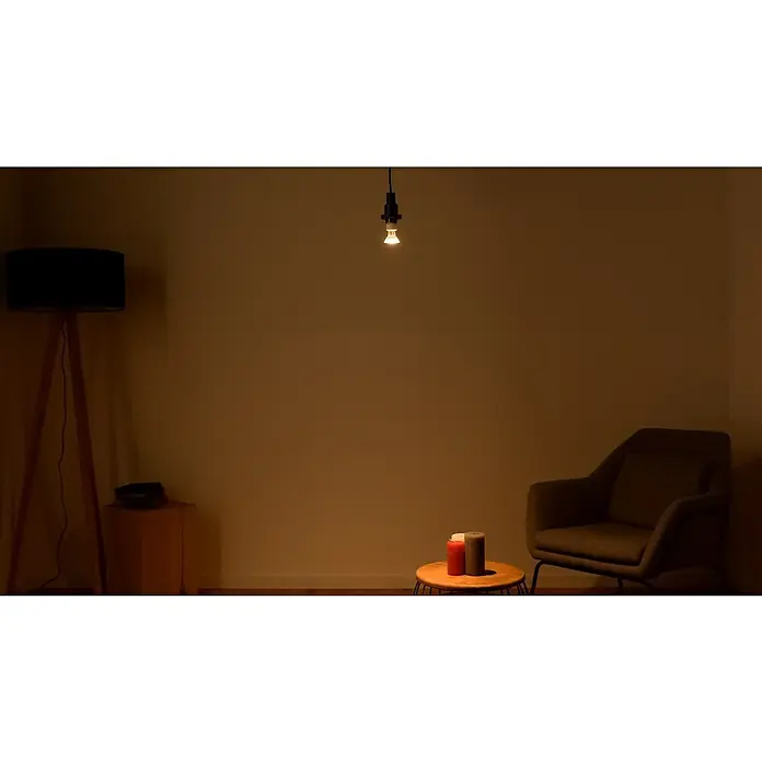 Osram LED-Lampen Set Reflektor GU10 - GU10, Nicht Dimmbar, Warmweiß, 230 lm, 2,6 W, 5 Stk. - Gemütliches Interieur mit Stehlampe, freihängender Glühbirne, Sessel und Tisch mit Kerzen in warmen Farbtönen für eine behagliche Atmosphäre.
