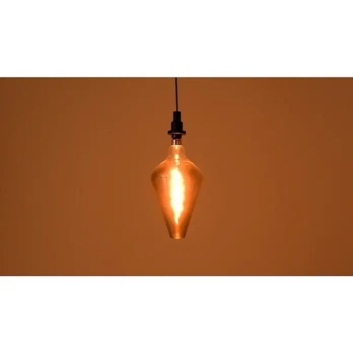 Osram LED-Lampe Vintage Edition 1906 Glühlampenform E27 - E27, Dimmbar, Warmweiß, 140 lm, 4 W - Nahaufnahme einer hängenden, glühenden Edison-Glühbirne mit einer ungewöhnlichen Form, die ein warmes Licht in einem Raum ausstrahlt.
