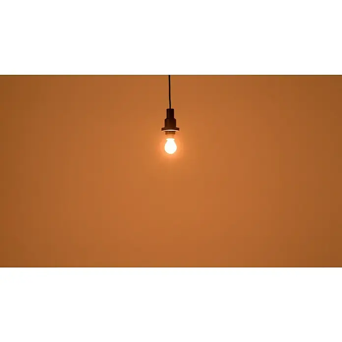 Osram LED-Lampe Vintage Edition 1906 Birnenform E14 - E14, Dimmbar, Warmweiß, 250 lm, 34 W - Eine einzelne Glühbirne hängt von der Decke und strahlt warmes Licht aus, das den Raum in einen sanften Farbton taucht.