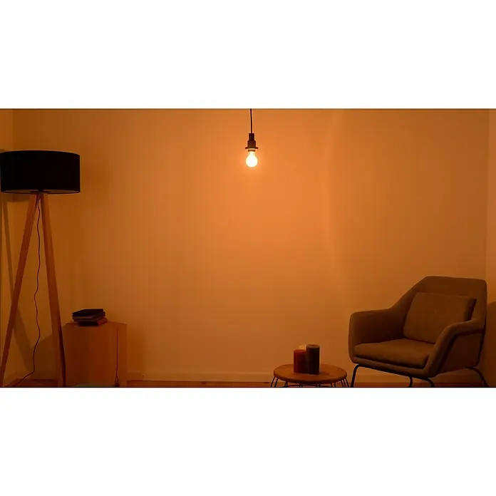 Osram LED-Lampe Vintage Edition 1906 Glühlampenform E27 - E27, Dimmbar, Warmweiß, 400 lm, 4,8 W, Birne, Gold - Elegantes Interieur mit Stehlampe, Pendelleuchte, Sessel und Beistelltisch mit Kerzen. Warmes, einladendes Lichtambiente für gemütliche Stunden.