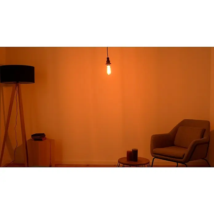 Osram LED-Lampe Vintage Edition 1906 Birnenform E27 - E27, Dimmbar, Warmweiß, 500 lm, 11 W, Smoke - Das Bild zeigt eine moderne Stehlampe mit einem schwarzen Lampenschirm und einem Holzstativ in einem gemütlichen Wohnzimmer.