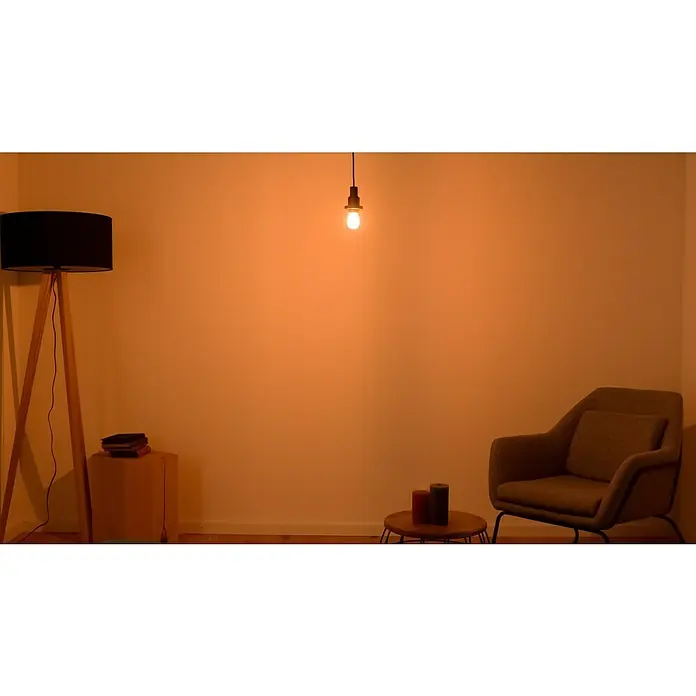 Ledvance LED-Lampe Glühlampenform E27 klarE27, Nicht Dimmbar, Warmweiß, 840 lm, 4 W - Eine gemütliche Leseecke mit Stehlampe, Sessel und sanfter Beleuchtung, die eine warme Atmosphäre schafft.