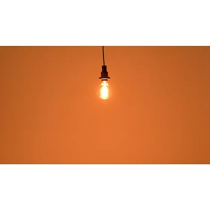 Osram LED-Lampe Vintage Edition 1906 Globe-Form E27 - Durchmesser: 9,5 cm, E27, Dimmbar, Warmweiß, 360 lm, 7,8 W - Glühbirne mit Glühfaden, an einem schwarzen Kabel hängend, spendet warmes, stimmungsvolles Licht vor orangefarbenem Hintergrund.