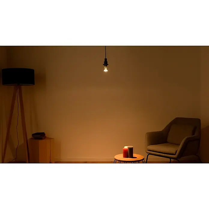 Osram LED-Lampen Set Reflektor GU10 - GU10, Nicht Dimmbar, Warmweiß, 350 lm, 4,3 W, 5 Stk. - Die gemütliche Szene zeigt eine minimalistische Hängelampe, eine Stehlampe, einen Sessel und Kerzen, die eine warme Atmosphäre schaffen.