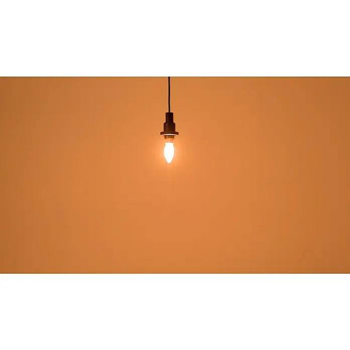 Osram LED-Lampe Vintage Edition 1906 Birnenform E14 - E14, Dimmbar, Warmweiß, 250 lm, Kerze, Gold - Glühbirne mit sanftem Licht an schwarzem Kabel vor orangefarbenem Hintergrund, ideal für stimmungsvolle Beleuchtung.