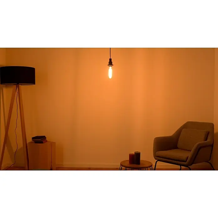 Osram LED-Lampe Vintage Edition 1906 Globe-Form E27 - E27, Dimmbar, Warmweiß, 470 lm, 4,8 W - Das Bild zeigt eine minimalistische Inneneinrichtung mit einer Stehlampe, einem Edison-Leuchtmittel, einem Sessel und Dekorationen.