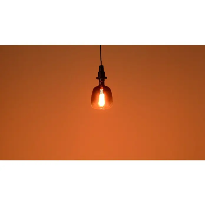 Osram LED-Lampe Vintage Edition 1906 Globe-Form E27 - E27, Dimmbar, Warmweiß, 150 lm, 4,5 W - Nahaufnahme einer hängenden Glühbirne, die warmes, bernsteinfarbenes Licht ausstrahlt und eine gemütliche Atmosphäre erzeugt.