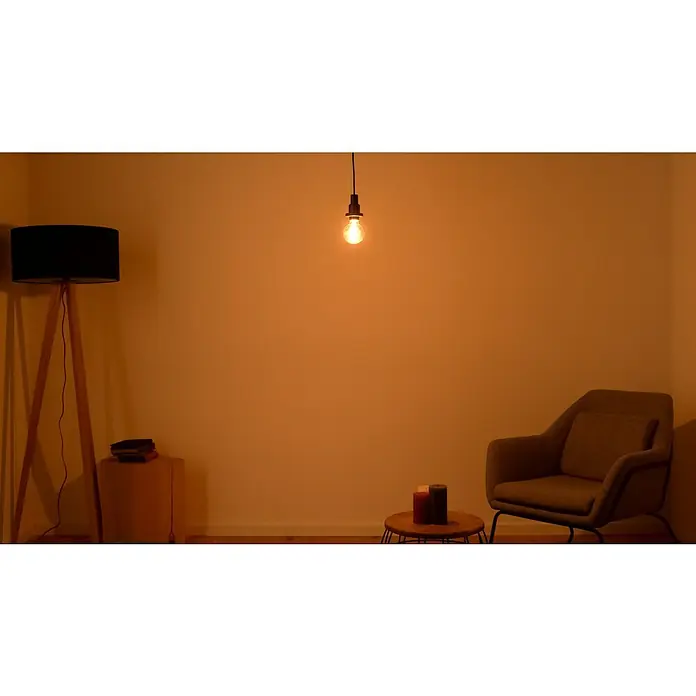 Osram LED-Lampe Vintage Edition 1906 Globe-Form 80 E27 - E27, Dimmbar, Warmweiß, 420 lm, 4,8 W - Wohnzimmer mit sanftem Licht, einer Stehlampe und einem Sessel, die einladende Atmosphäre schaffen. Der Raum strahlt Wärme und Behaglichkeit aus.