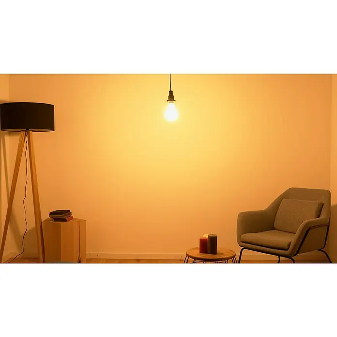 Osram LED-Lampe Glühlampenform E27 matt - E27, Nicht Dimmbar, Warmweiß, 3.452 lm, 24 W - Ein gemütliches Interieur mit einem Stehlampe, einem Sessel und einer Glühbirne, die eine warme Atmosphäre schaffen. Ideal zum Entspannen.
