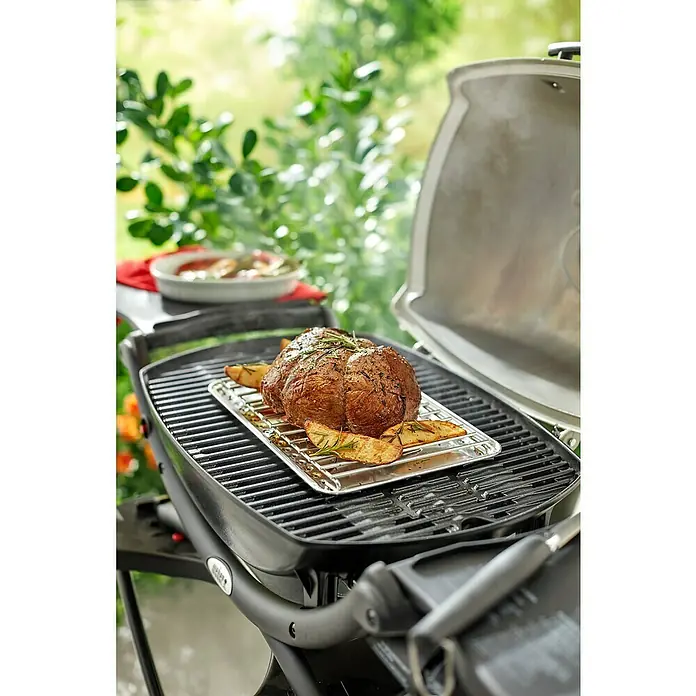 Weber Hitzeschild - Passend für: Weber Q 100 / Q 1000 - Serie - Ein Weber Grill mit einem saftigen Braten und Kartoffeln auf dem Rost, bereit zum Genießen im Freien.