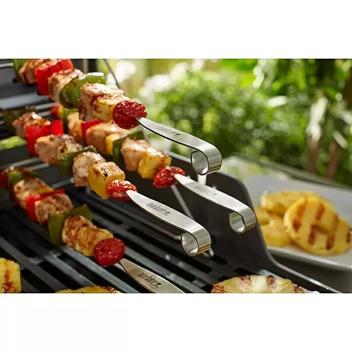 Weber Grillspieß - Länge: 34 cm, 4 -tlg. - Weber-Edelstahlspieße mit gegrillten Hähnchen- und Gemüsespießen auf einem Grill, mit gegrillter Ananas auf einem Teller.
