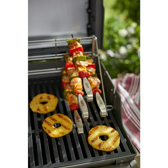 Weber Grillspieß - Länge: 34 cm, 4 -tlg. - Ein Grill mit leckeren Fleischspießen und gegrillten Ananasscheiben auf dem Rost. Die Weber-Spieße sind perfekt zum Grillen von Schaschlik.