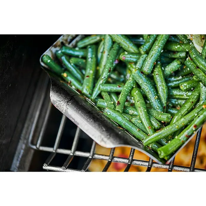 Weber Style Gemüsekorb - Edelstahl, 29,5 x 35 cm - Eine Schale mit frischen, grünen Bohnen, verfeinert mit Gewürzen, liegt auf einem Grillrost und wartet darauf, serviert zu werden.
