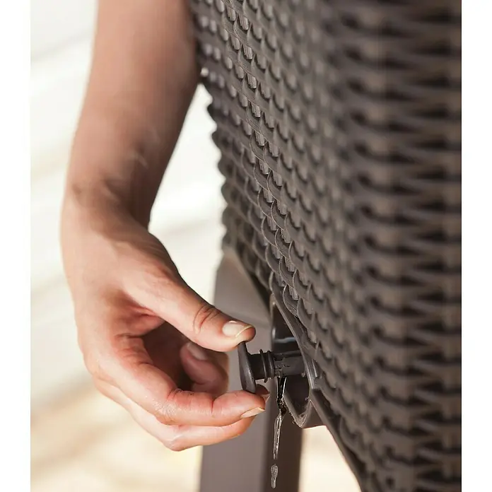 Keter Hochbeet Easy Growing - 114 x 49,3 x 75,7 cm, Kunststoff, Dunkelgrau - Frau betätigt den Wasserhahn an einem braunen Rattan-Regentonnenständer, aus dem Wasser tropft, was die Funktionalität des Produkts hervorhebt.