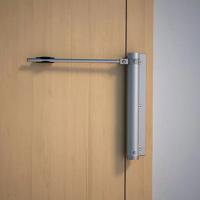 Abus Türschließer TS40 AL - Silber, Geeignet für: Zimmertüren - Silberner Türschließer aus Metall, montiert an einer hellen Holztür und einem Türrahmen.
