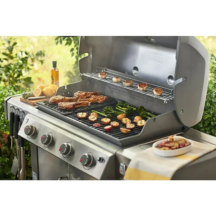 Weber Grilleinsatz Sear-Grate - Passend für: Weber Gasgrills Genesis II - Nahaufnahme eines Weber Grills mit Steaks, Gemüse und Knoblauch, der im Freien für ein köstliches kulinarisches Erlebnis sorgt.