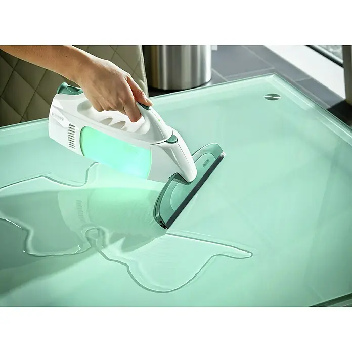 Leifheit Akku-Fenstersauger Dry & Clean - 1 Akku, Behältervolumen: 0,1 l - Ein Leifheit Fensterwischer im Einsatz auf einem Tisch. Das Gerät ist weiß und grün und hinterlässt eine saubere Oberfläche.