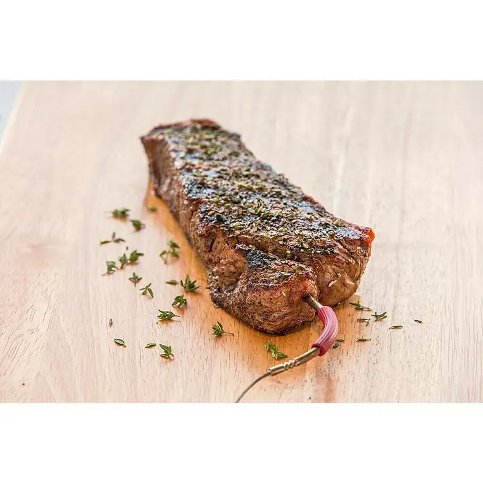 Weber Ersatz-Messfühler iGrill Pro - Passend für: Weber Thermometer iGrill, Kerntemperaturmessung - Ein perfekt gebratenes Steak, gewürzt mit Kräutern, liegt auf einem Holzbrett und wird mit einem Thermometer auf seine Kerntemperatur geprüft.