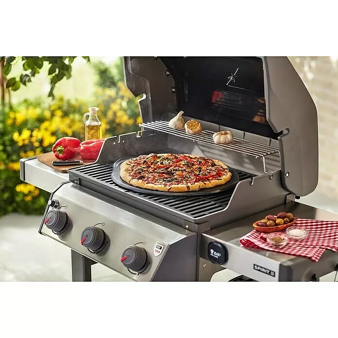 Weber Pizzastein - L x B: 4,6 x 42 cm, Durchmesser: 42 cm, Cordierit, Stein - Grauer Gasgrill mit Edelstahl-Elementen, Pizza auf Stein und Röstknoblauch, im Freien.