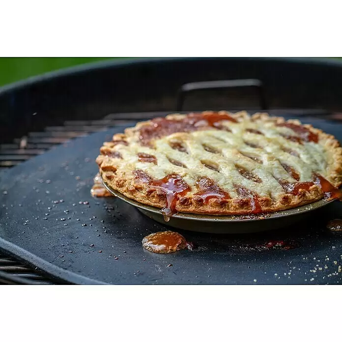 Weber Pizzastein - L x B: 4,6 x 42 cm, Durchmesser: 42 cm, Cordierit, Stein - Goldbrauner Gitterkuchen mit sprudelnder Fruchtfüllung, der auf einer dunklen Grillplatte mit karamellisierten Tropfen backt.
