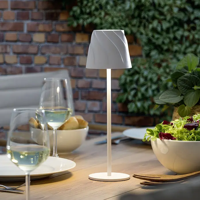Starlux Akku-Tischleuchte Loreo - 4 W, L x B x H: 11 x 11 x 36 cm, Weiß, Warmweiß - Elegante Tischleuchte auf einem gedeckten Tisch mit Wein und Speisen im Freien, die eine stimmungsvolle Atmosphäre schafft.