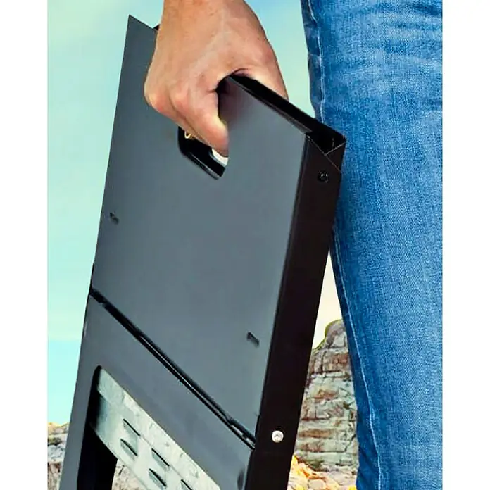 Grillstar Holzkohlegrill - Grillfläche (B x T): 44 x 29 cm, Schwarz - Eine Person hält einen zusammengeklappten schwarzen tragbaren Grill mit Tragegriff vor blauem Himmel und Felsformationen.