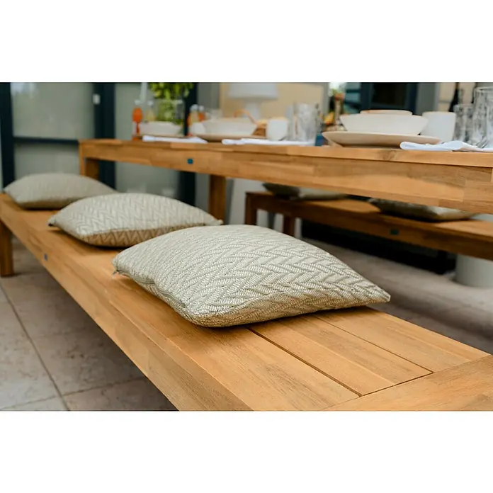 Sunfun Laura Gartenbank - B x T x H: 270 x 42 x 45 cm, Akazie, Braun - Helle Sitzkissen mit Fischgrätenmuster auf einer langen Holzbank, die zu einem Esstisch im Freien gehört.