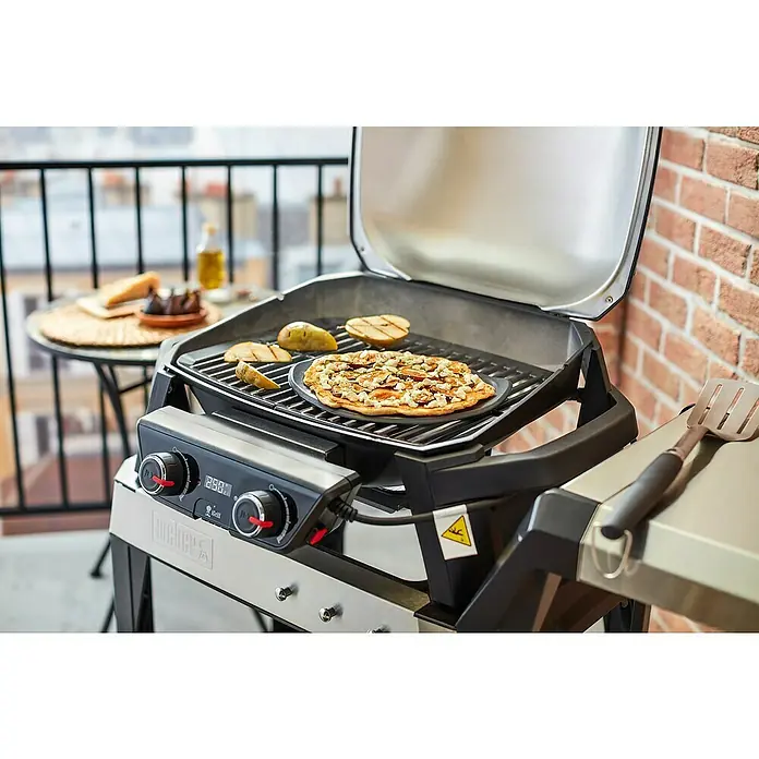 Weber Pizzastein - Durchmesser: 26 cm, Steinzeug - Bild eines Weber Grills mit Pizza und Birnen, die darauf zubereitet werden, ideal für kulinarische Erlebnisse im Freien.