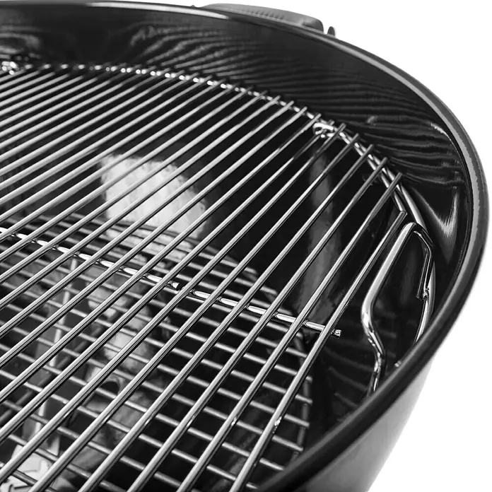 Weber Kugelgrill Original Kettle E-5730Durchmesser Grillfläche: 54 cm, Schwarz/Silber - Nahaufnahme eines schwarzen Grills mit glänzenden Metallrosten, der bereit für das Grillen im Freien ist.