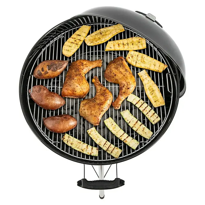 Weber Kugelgrill Original Kettle E-5730Durchmesser Grillfläche: 54 cm, Schwarz/Silber - Grillgut auf einem Holzkohlegrill, darunter Hühnchen, Süßkartoffeln und Zucchini. Perfekt für einen sommerlichen Grillabend im Freien.