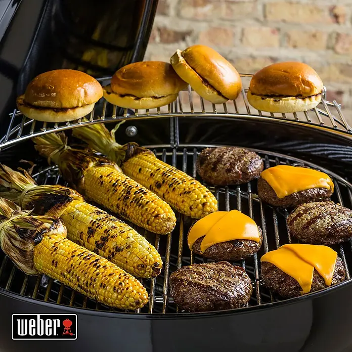 Weber Master-Touch GBS Kugelgrill E-5750 - Durchmesser Grillfläche: 57 cm, Schwarz - Gegrillte Burger, Maiskolben und Brötchen auf einem Weber Grill.